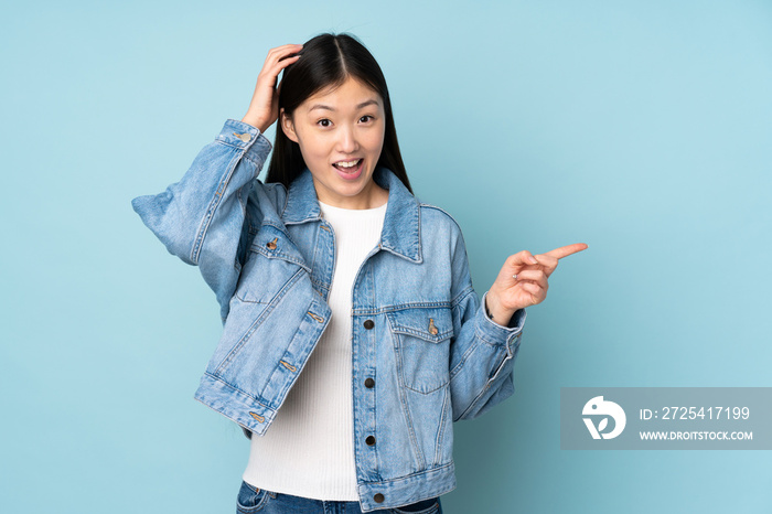 Young asian woman isolated on background surprised and pointing finger to the side