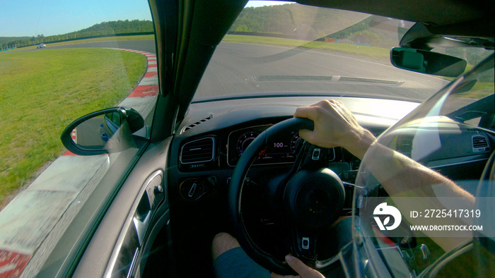 CLOSE UP: Man wearing a helmet races his fast car along the fun racetrack.