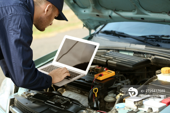 Mechanic using computer diagnostics while repairing car