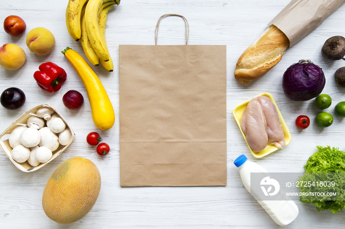 Overhead, healthy raw food with paper bag on white wooden surface. Cooking food background. Flat lay