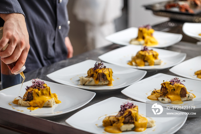 Chef pours sauce on plates