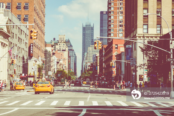 New York City street road in Manhattan at summer time, many cars, yellow taxis and busy people walk 