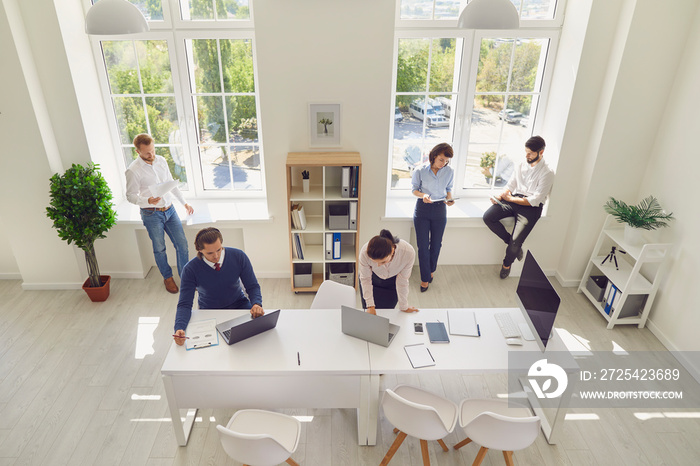 Serious young company employees preparing for corporate meeting in spacious office room