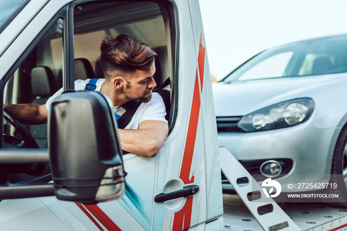 Handsome middle age man working in towing service on the road. Roadside assistance concept.