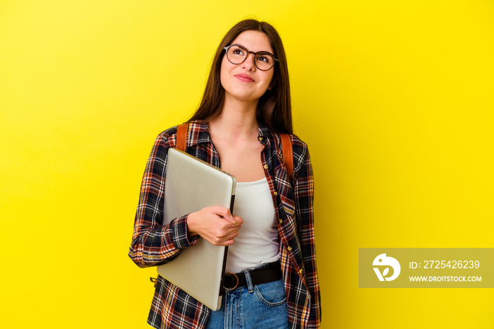 Young caucasian student woman holding a laptop isolated on pink background dreaming of achieving goa