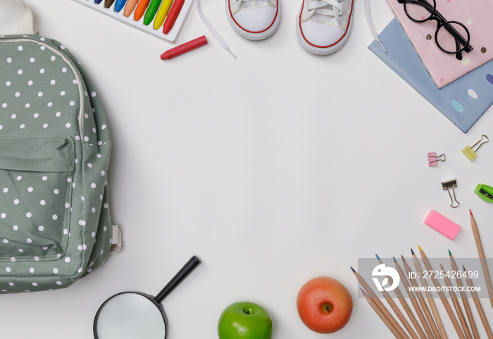 Creative flatlay of education white table with backpack, student books, shoes, colorful crayon, eye 
