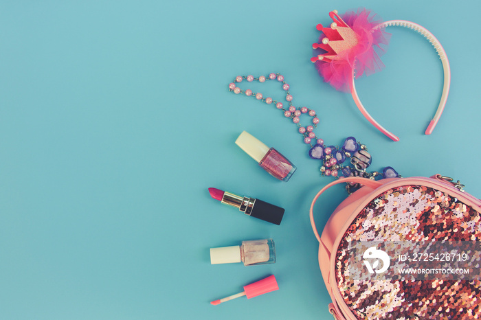 Female backpack with cosmetics and womens accessories on blue background. Top view. Toned image.