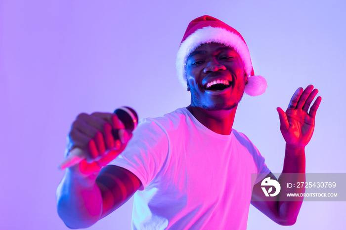 Christmas music. Cool black guy in Santa hat singing holiday song, using microphone, performing kara