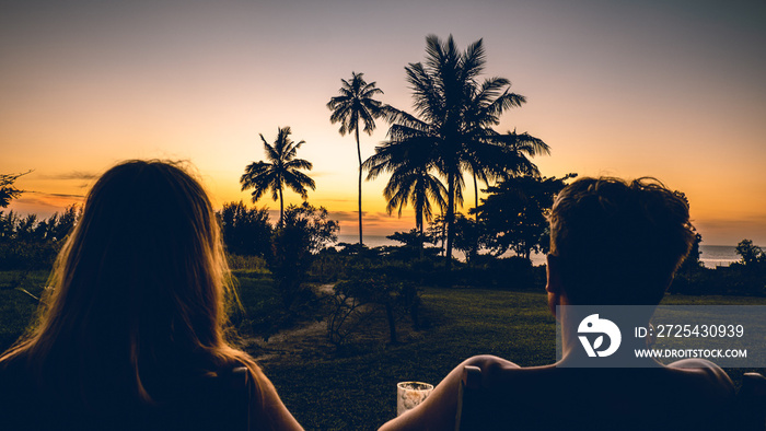 a young couple watching the sunset with palm trees in Tanzania Africa