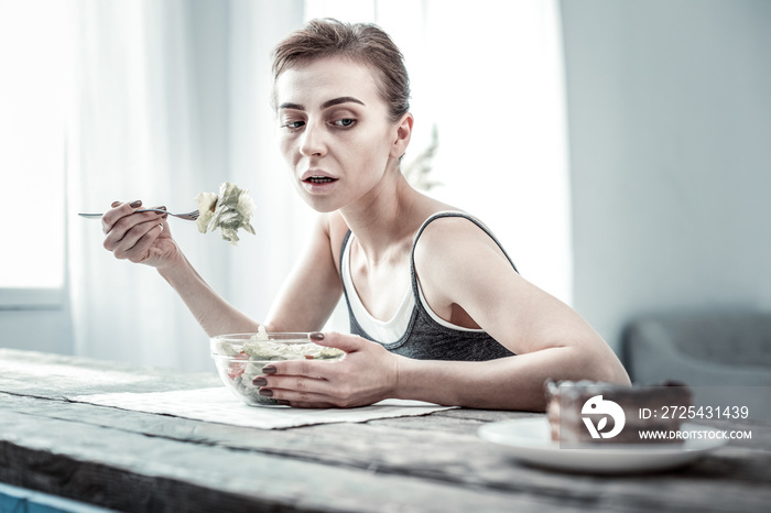 Hungry slim woman staring at piece of cake