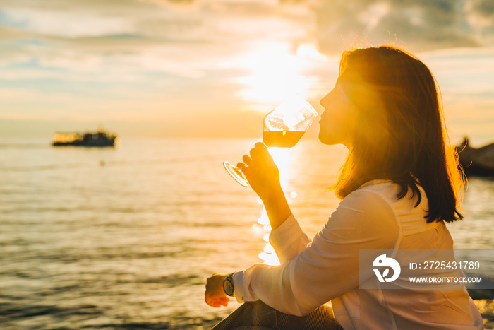 woman drink wine at sea beach looking on sunset