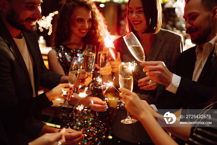 年轻的朋友们庆祝新年，拿着孟加拉灯和酒杯喝酒。寒假。