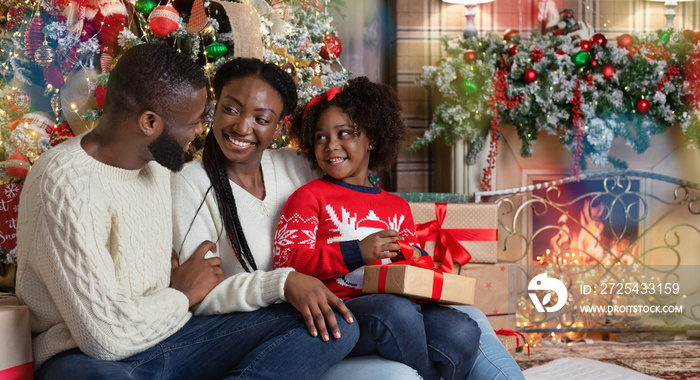 Happy black couple and their little daughter enjoying Christmas together