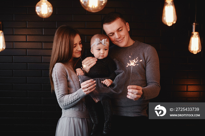 portrait of happy family, mom, dad and baby girl with sparklers in front. family in anticipation of 