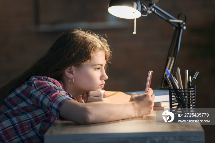 Teenage girl with mobile phone late in evening