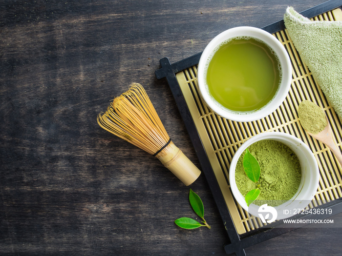 碗里的绿色抹茶和木桌上的竹搅拌器，俯视图