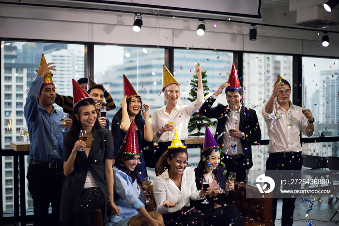 在办公室的新年派对上微笑的年轻商界人士，为新年名人喝香槟