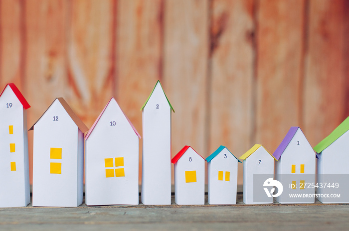 Christmas advent calendar of paper houses on wooden background