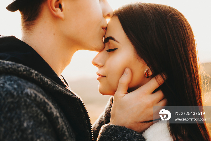 Side view portrait of a beautiful young european couple where man is kissing his girlfriend forehead