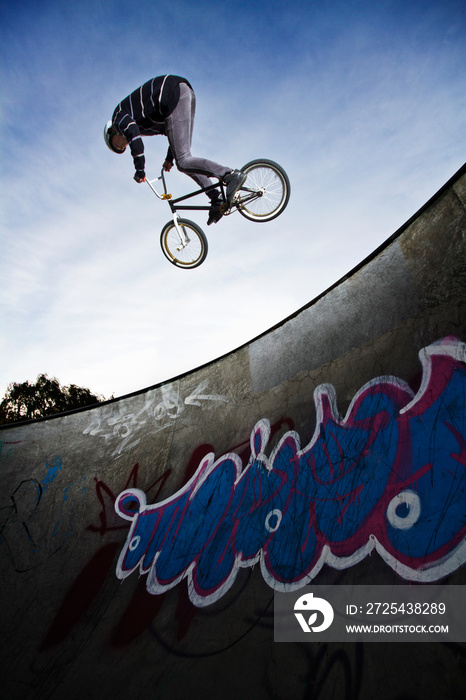 Low angle view of man performing stunt while cycling on sports ramp