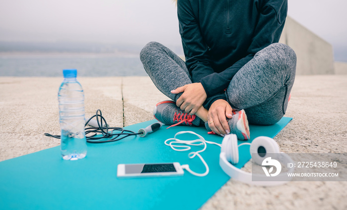 Low section of woman sitting on yoga mat with sport accessories