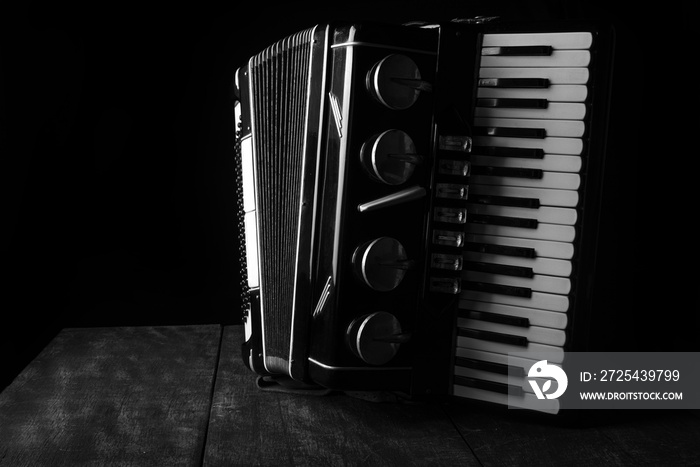 Old accordion on rustic wooden surface with black background and Low key lighting, selective focus.