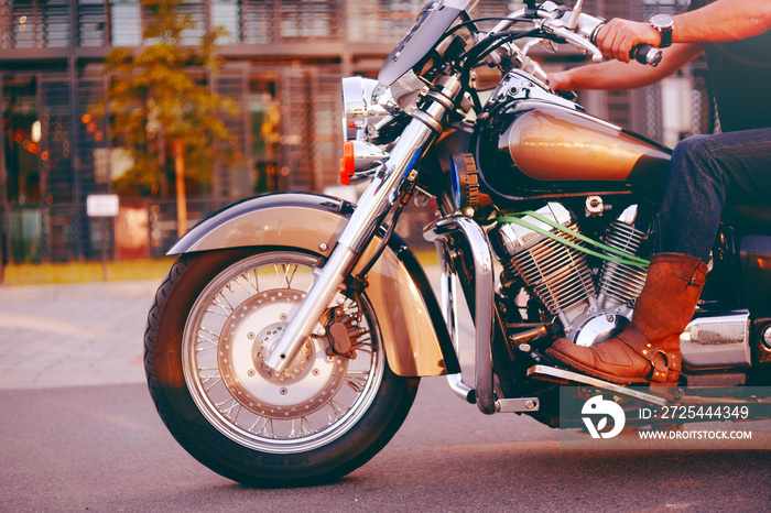 Biker riding on a motorcycle. Bottom view of the legs in leather boots. A man near the office center