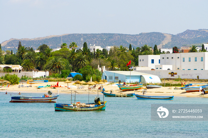 Blick auf den Strand und das Meer bei Hammamet mit Fischerbooten im Wasser.