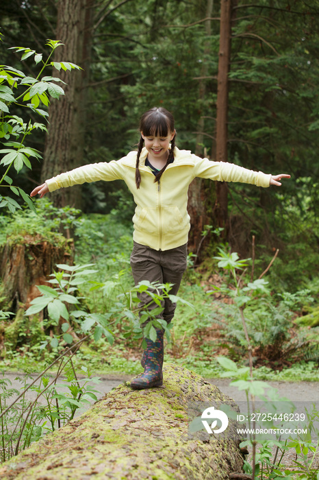 young girl balancing on fallen tree