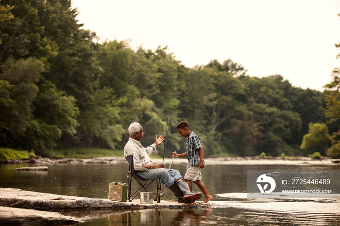 Boy and grandfather fishing in river