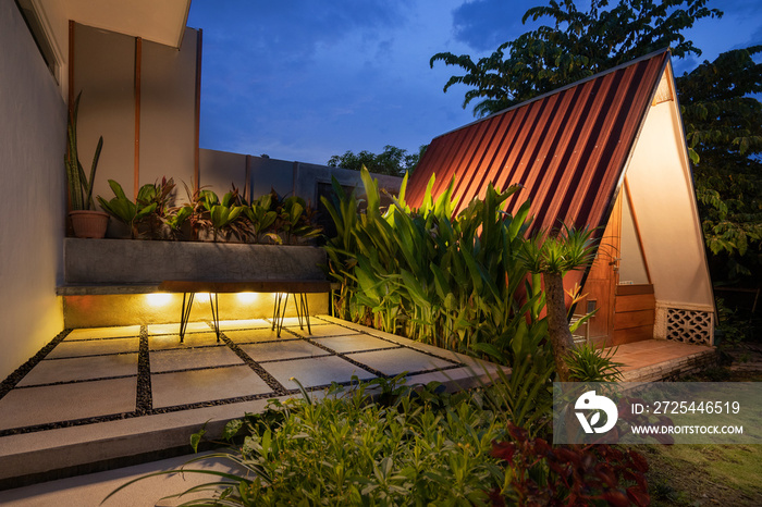 tropical Backyard Garden Illumination with cabin. Illuminated Garden at Night with Various of Plants