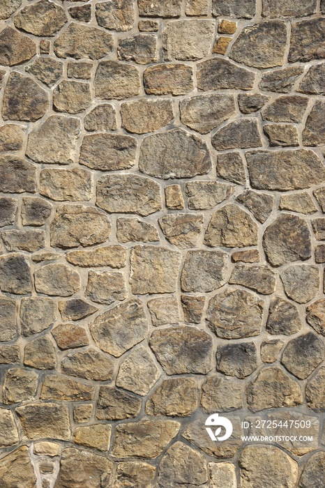 古代马赛克石墙的垂直细节，带有不规则的石头形状和对比的gro