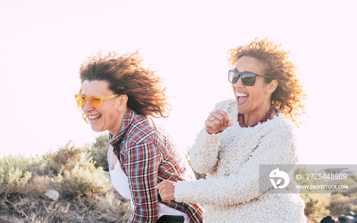 Two playful happy cheerful middle age women have lot of fun playing together - craziness and playful