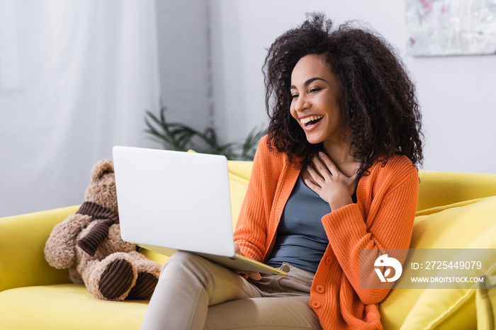 joyful african american freelancer using laptop at home