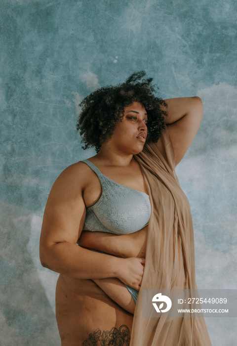 portrait of a plus size afro-indigenous person standing looking towards the sun hand in hair