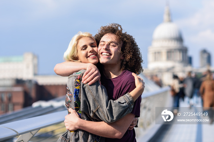 Happy couple hugging by Millennium bridge, River Thames, London.