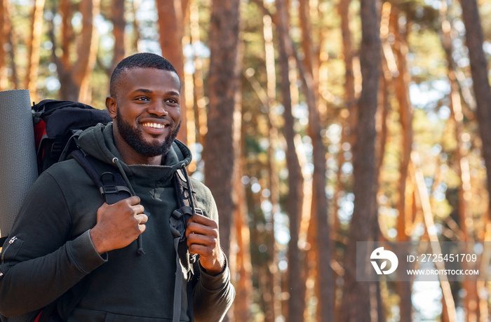 African man with backpack hiking by forest