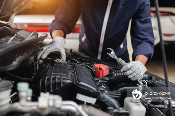 Automobile mechanic repairman hands repairing a car engine automotive workshop with a wrench, car se