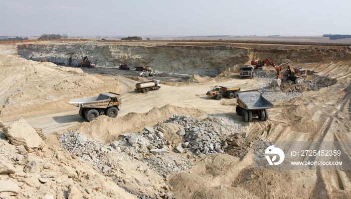 Open Pit Coal Mining - Large Rock Dump Trucks and Excavators digging and hauling in an open pit coal