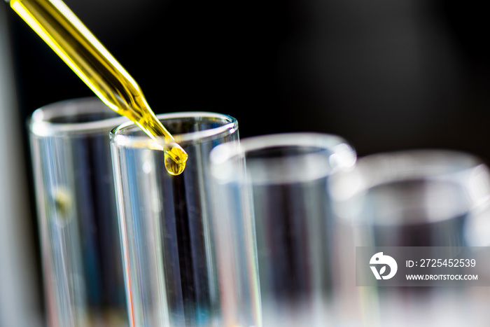 Using dropper sampling oil or chemical liquid drop to test tube with lab glassware in laboratory bac