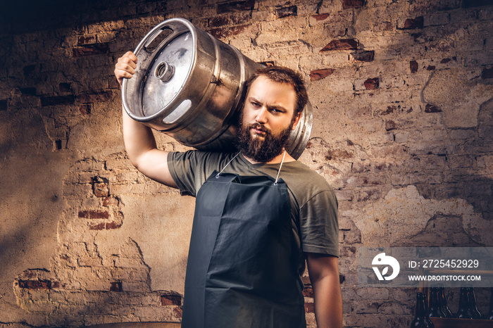 Brewer in apron holds barrel with craft beer at brewery factory.