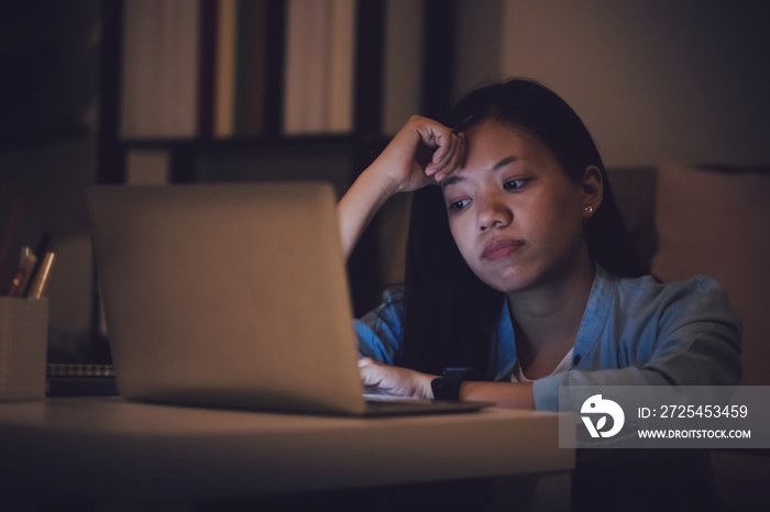 亚洲女学生或女商人晚上工作到很晚。集中注意力，坐在办公桌前昏昏欲睡