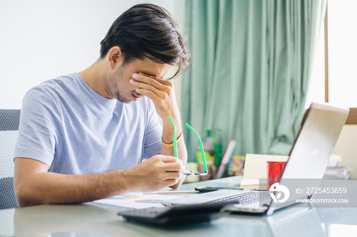 Young Asian office worker touching on the eyes due to tiredness from working computer for a long tim