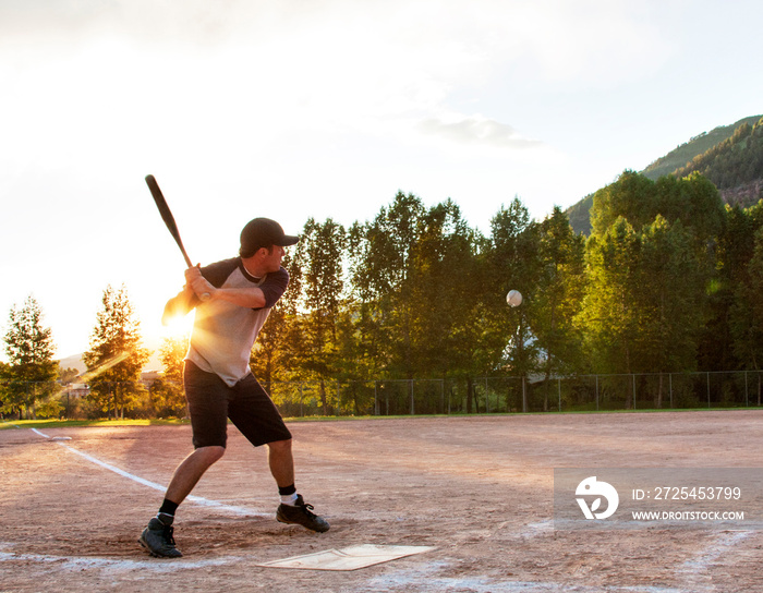 Softball player hitting ball in playing field