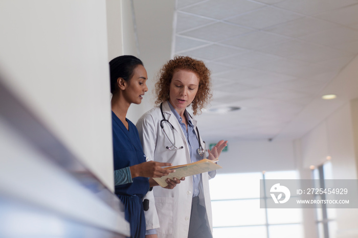 Female doctor and nurse consulting in hospital corridor