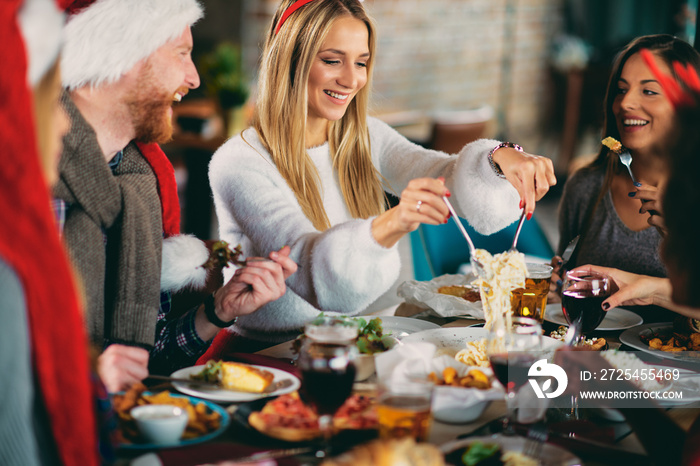 Friends having dinner at home at Christmas eve. Winter holidays concept.