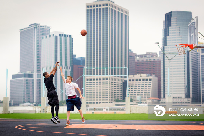 Young men playing basketball in court