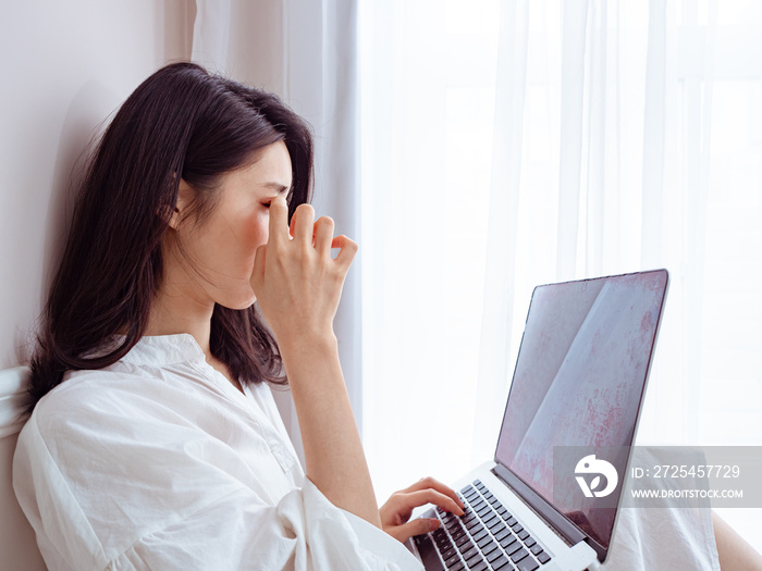 Asian young woman rubbing her tired eyes when using laptop.