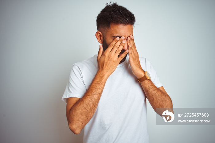 Young indian man wearing t-shirt standing over isolated white background rubbing eyes for fatigue an