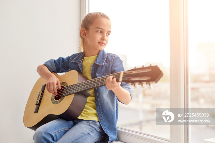 Girl playing guitar near window